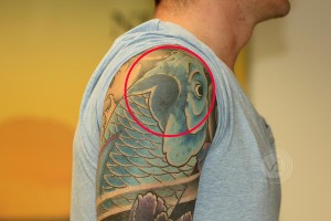 Old black tattoo faded under a new tattoo